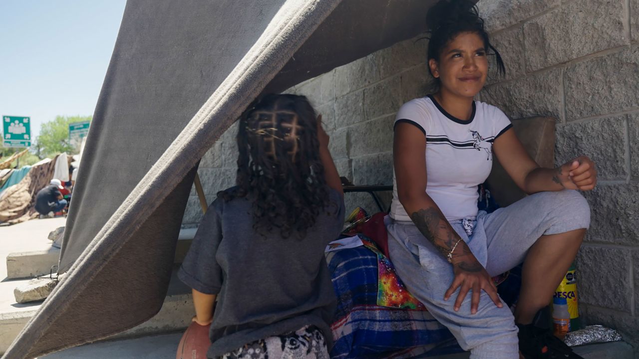  Janeysi Games sits under a blanket strung to a wall to provide shade in Ciudad Juárez. She said she wants to enter the US legally with her husband and four-year-old daughter but does not know when she will get an appointment.