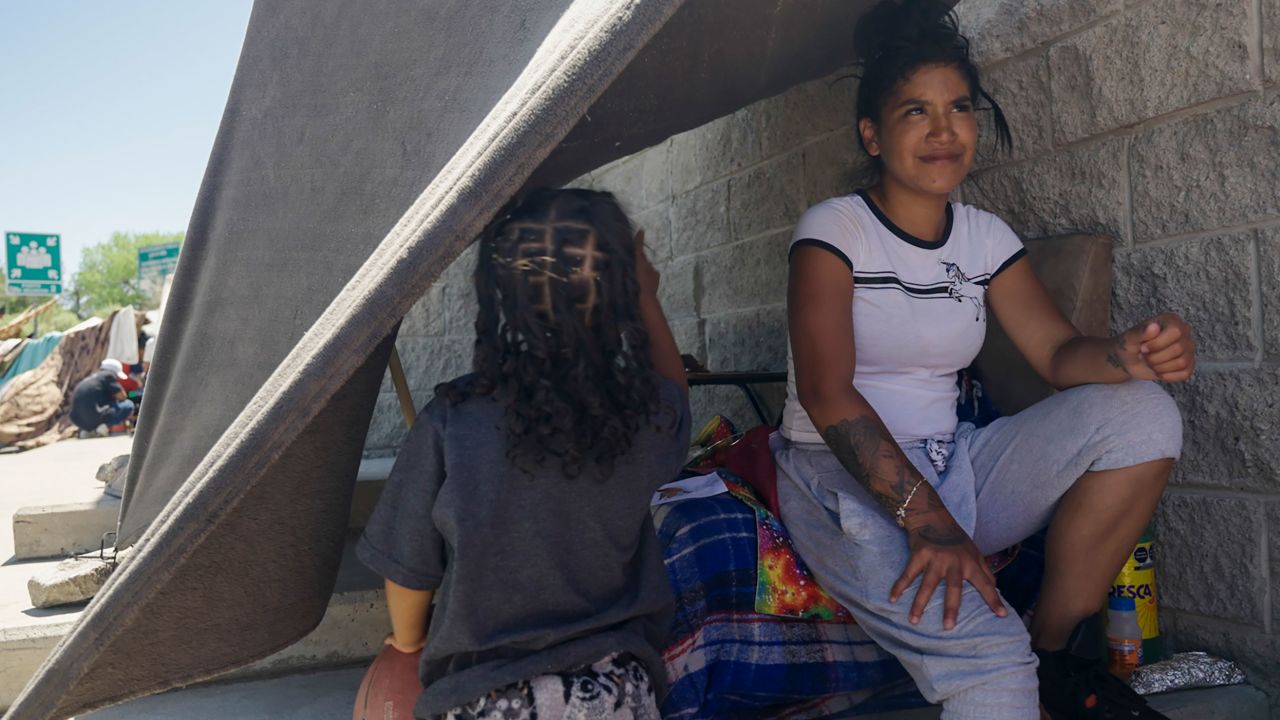 Janeysi Games sits under a blanket strung to a wall to provide shade in Ciudad Juárez. She said she wants to enter the US legally with her husband and four-year-old daughter but does not know when she will get an appointment.