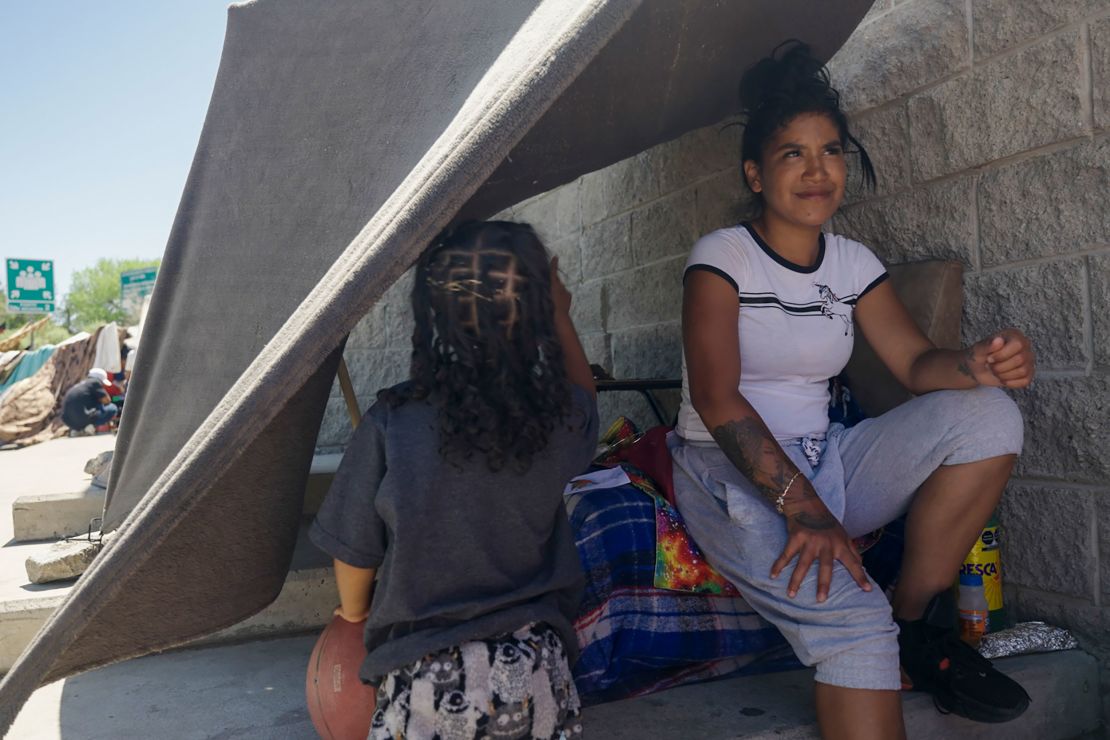  Janeysi Games sits under a blanket strung to a wall to provide shade in Ciudad Juárez. She said she wants to enter the US legally with her husband and four-year-old daughter but does not know when she will get an appointment.