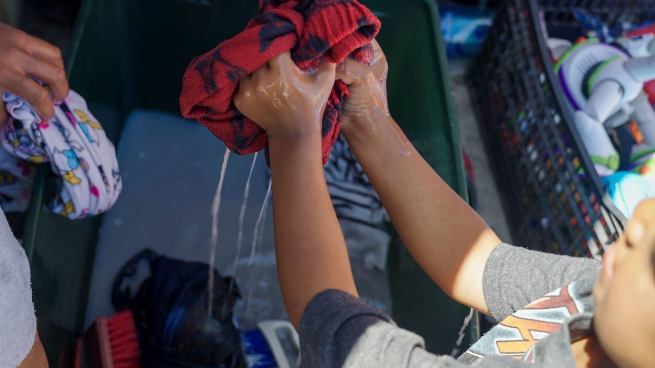 Janeysi Games washes clothes with her daughter.