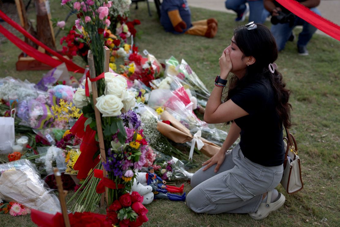 A mourner grieves Tuesday at a makeshift memorial at Allen Premium Outlets.