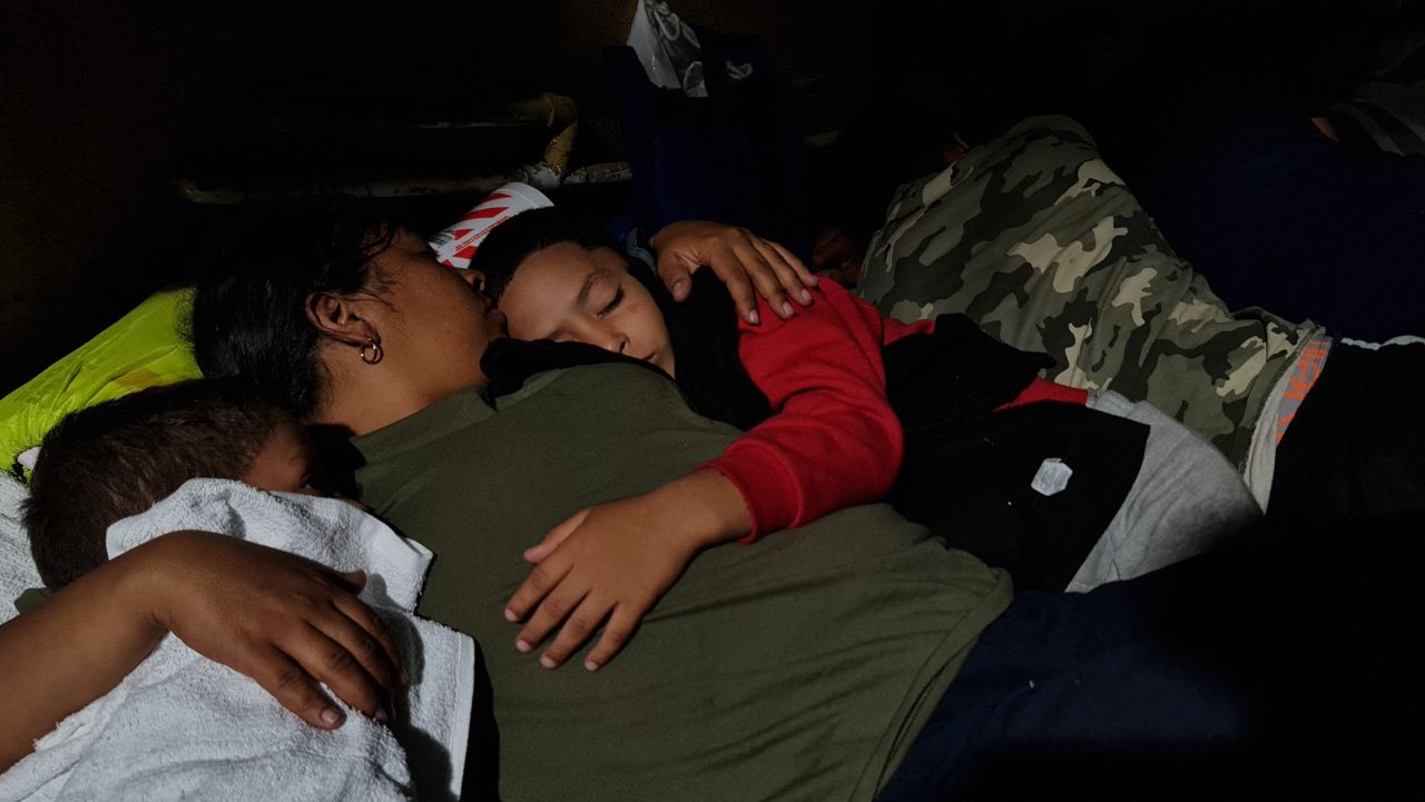 A mother holds her sleeping sons as they rest next to a gas station in Brownsville on May 6. She was waiting for her brother, who lives in Los Angeles, to buy them bus tickets so they could continue their trip into the United States to meet him.