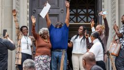 Patrick Brown, center in blue, raises his arms as he walks out a free man from Criminal District Court on Monday, May 8, 2023 in New Orleans after 20 years in jail for a rape the victim/survivor says he did not commit. (Chris Granger/The Advocate via AP)