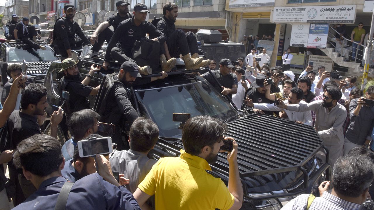 Private security personnel clear the way for a vehicle carrying Imran Khan arriving for his court appearance in Islamabad.