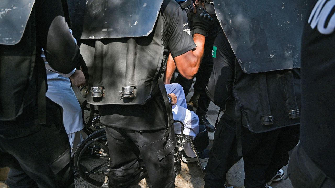 Security personnel escort Imran Khan as he sits in a wheelchair at the high court in Islamabad on Tuesday.