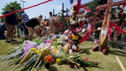 Visitors to a make shift memorial leave flowers in front of a large cross that has the words "Hope, Love, Allen", engraved into it at the mall where several people were killed, Monday, May 8, 2023, in Allen, Texas. (AP Photo/Tony Gutierrez)