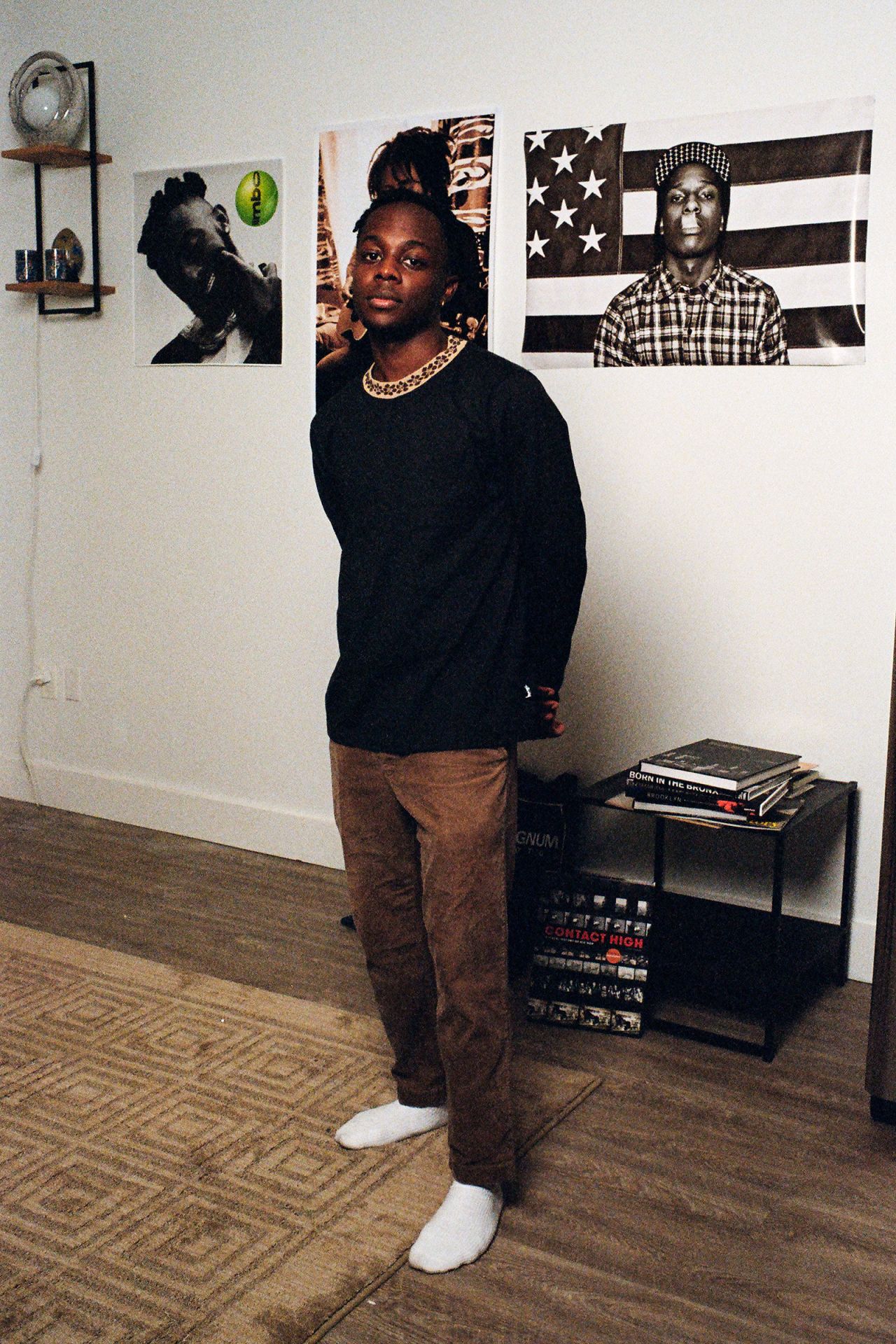 Akil, a participant in "Sowing Rice With Salt," poses in front of posters of American rappers.