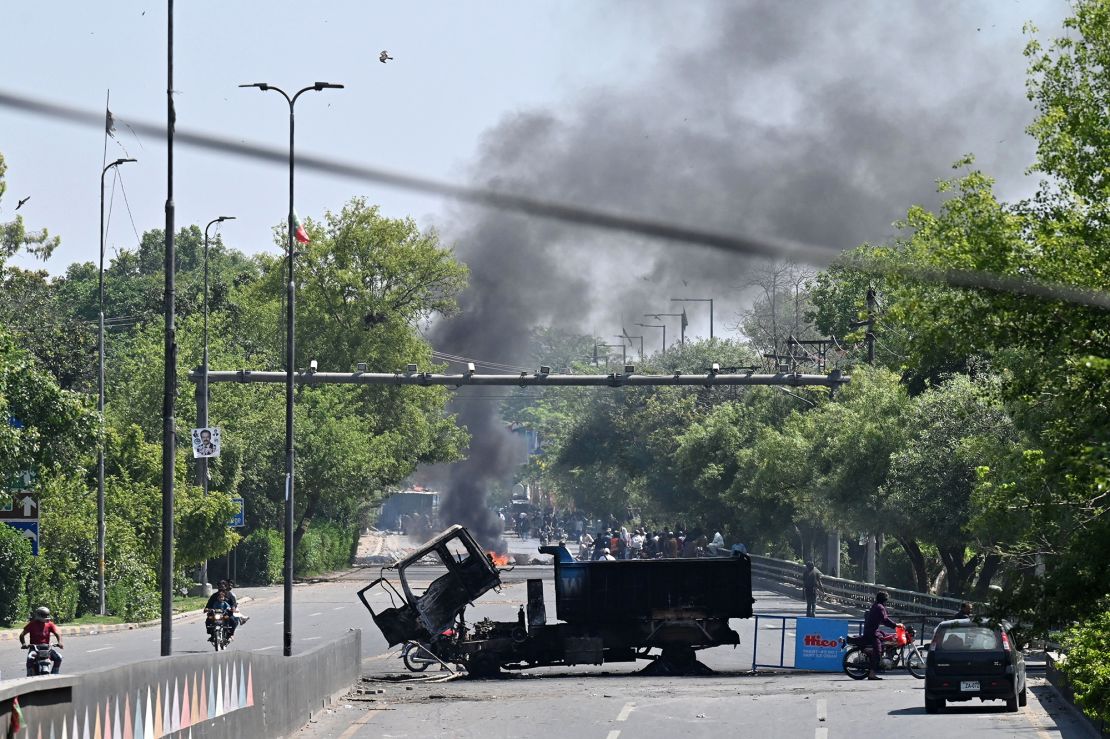 Motorists ride past burnt vehicles in front of the Zaman Park, a day after protests by Pakistan Tehreek-e-Insaf (PTI) party activists and supporters of former Prime Minister Imran Khan, in Lahore on May 10.