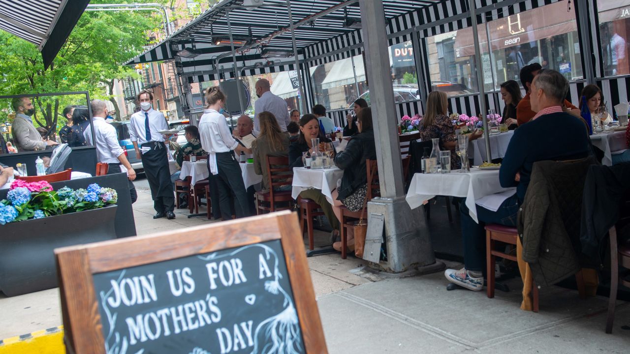 Customers dine at a restaurant's outdoor dining near a "Mother's Day" sign on Mother's Day.