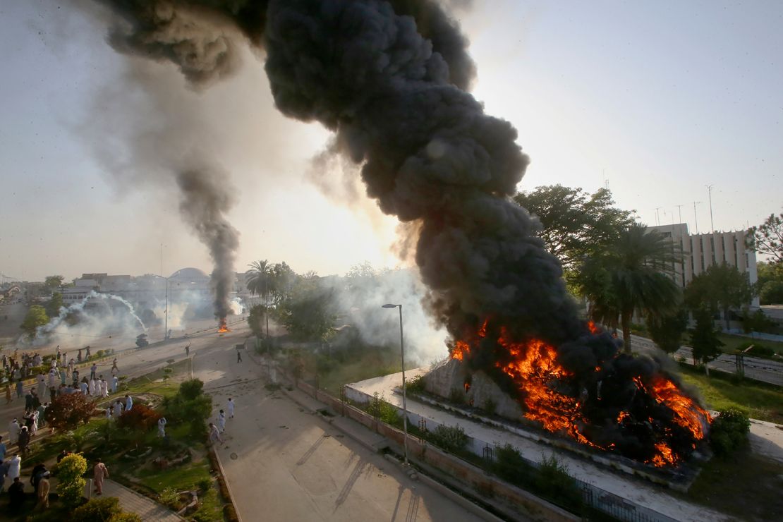 Smoke rises from fires set by angry supporters of Pakistan's former Prime Minister Imran Khan as police fire tear gas to disperse them during a protest in Peshawar on May 9. 