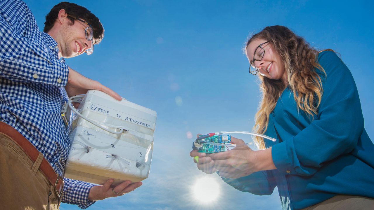 Die Geophysiker der Sandia National Laboratories (von links), Daniel Bowman und Sarah Albert, zeigen einen Infraschallsensor und die Box, die die Sensoren vor extremen Temperaturen schützt.