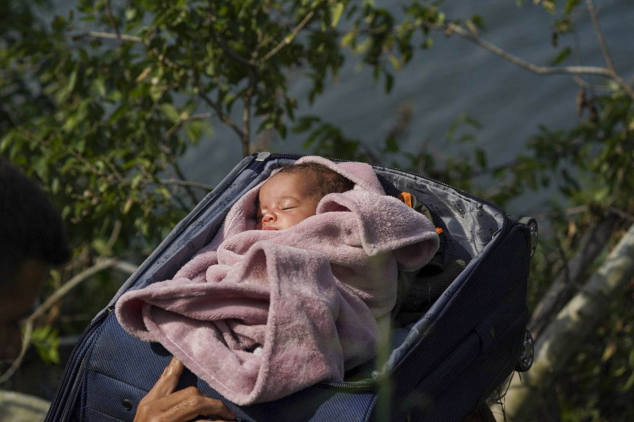 Migrants in Matamoros, Texas, carry a baby in a suitcase across the Rio Grande on their way to Texas on Wednesday, May 10.