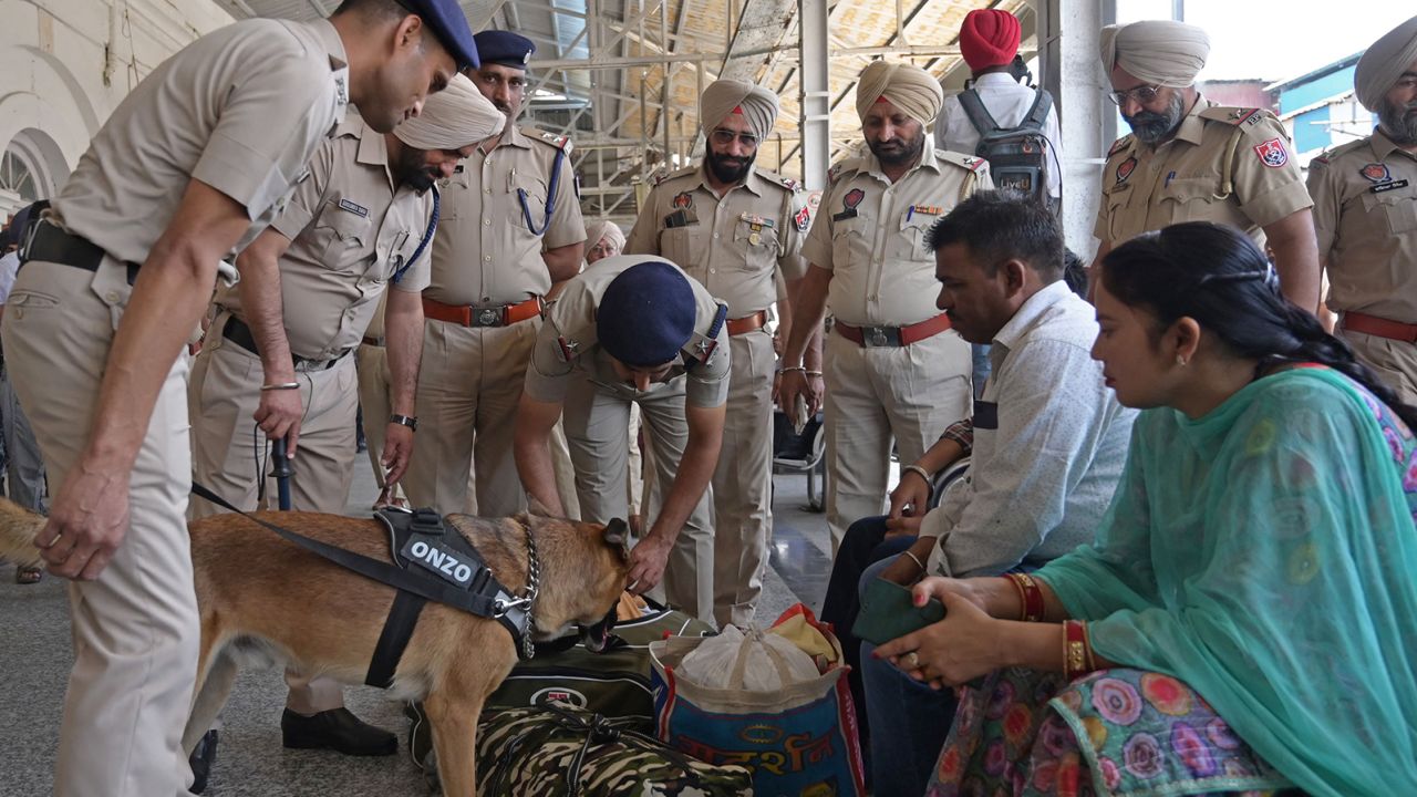 Policemen and a sniffer dog check the belongings of passengers at a railway station in Amritsar, India, on May 10, 2023, soon after a blast near the Golden Temple. 