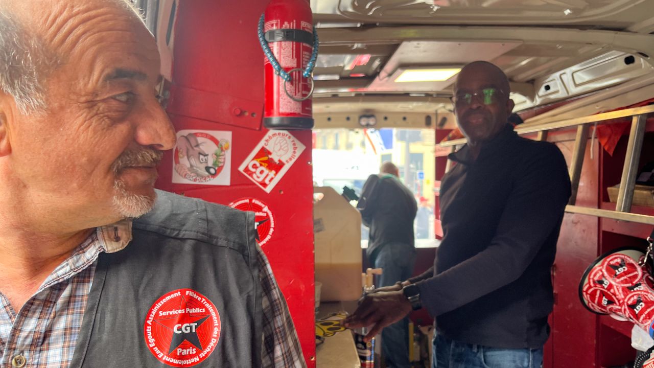 Patrice Clouzeau, left, and Jean-Michel Arcarde, refuse workers affiliated to France's CGT labor union, work in a sausage vending truck. 