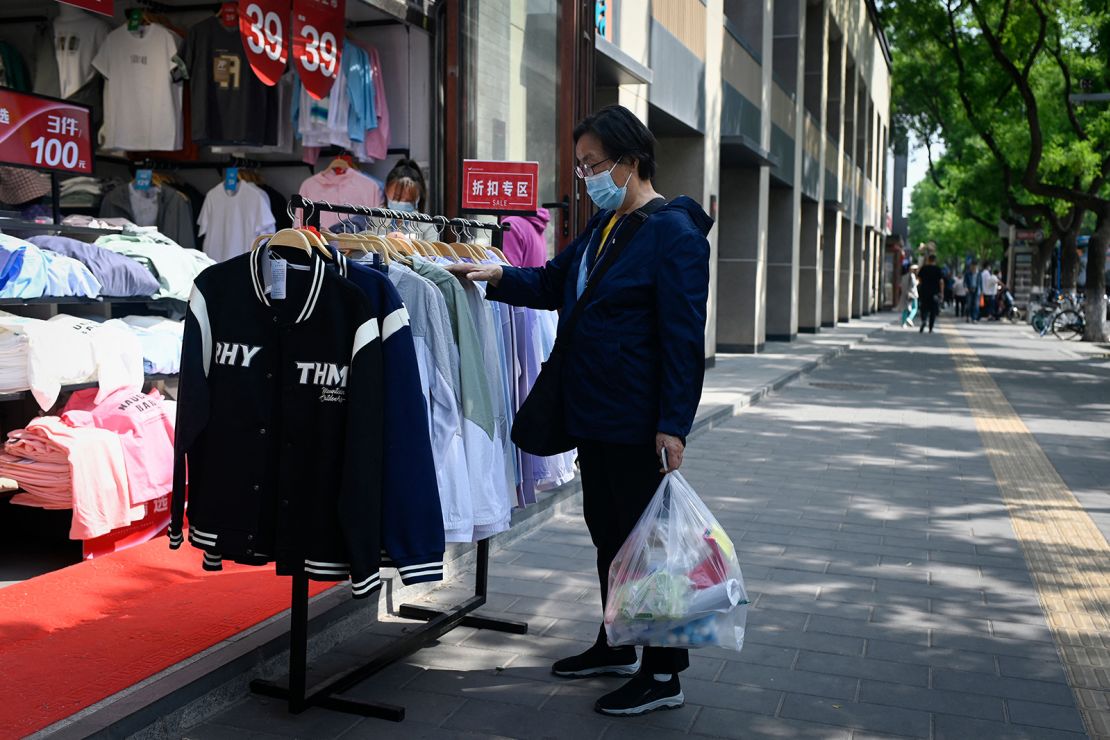 A customer browses through discount clothing displayed outside a shop in Beijing on May 10, 2023. 
