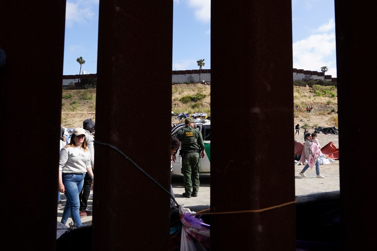 A US Border Patrol agent looks on as migrants wait to apply for asylum between two border walls in San Diego on Thursday, May 11.