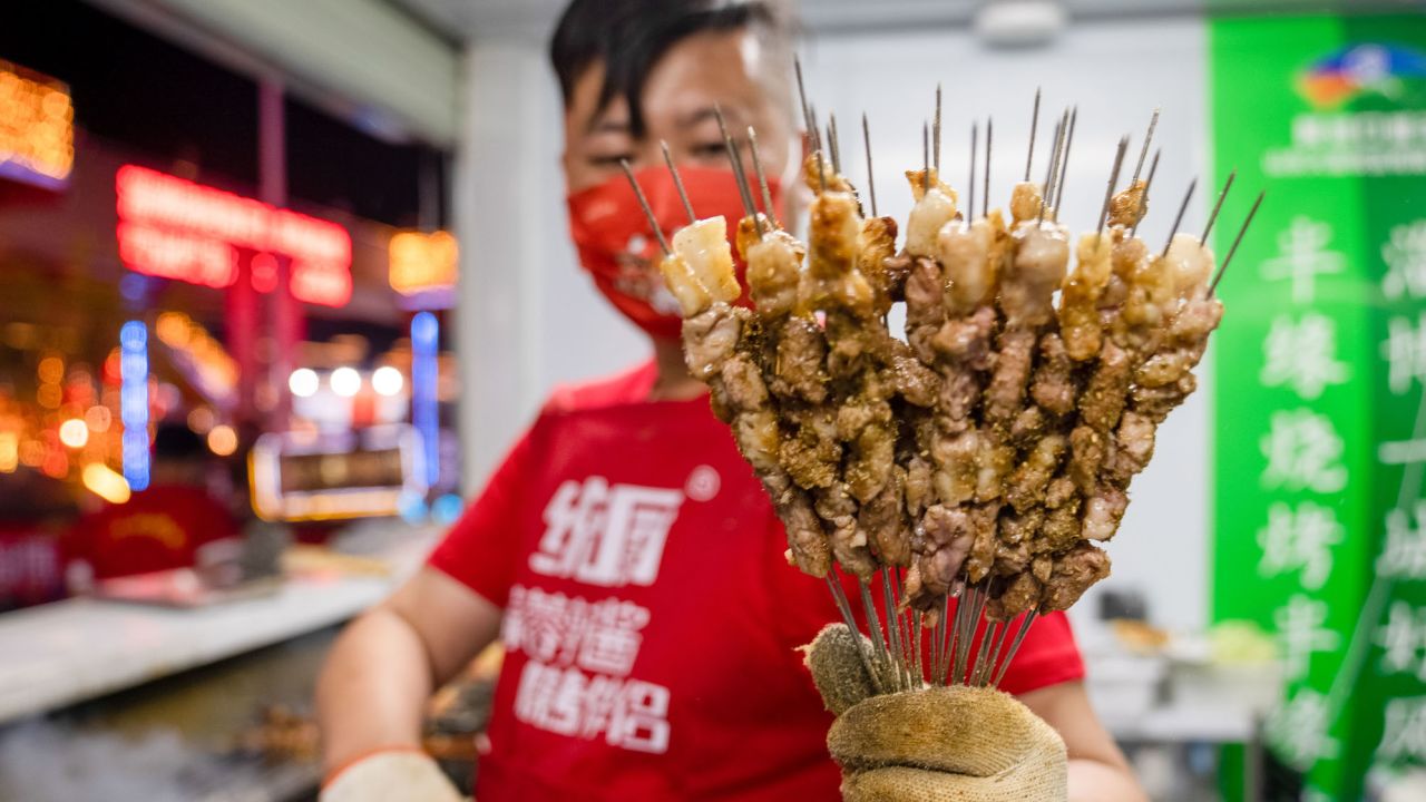 A shop owner shows off grilled meat during a barbecue festival on April 29, 2023 in Zibo. The city became a tourism hot spot after videos of its barbecue went viral online. 