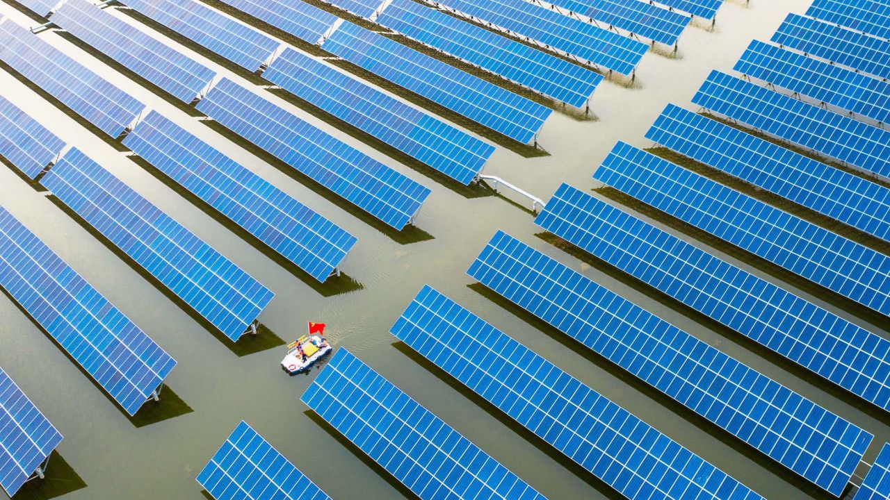Workers check solar panels installed atop a fish pond at a hybrid power station in May 2022 in China's central province of Anhui.