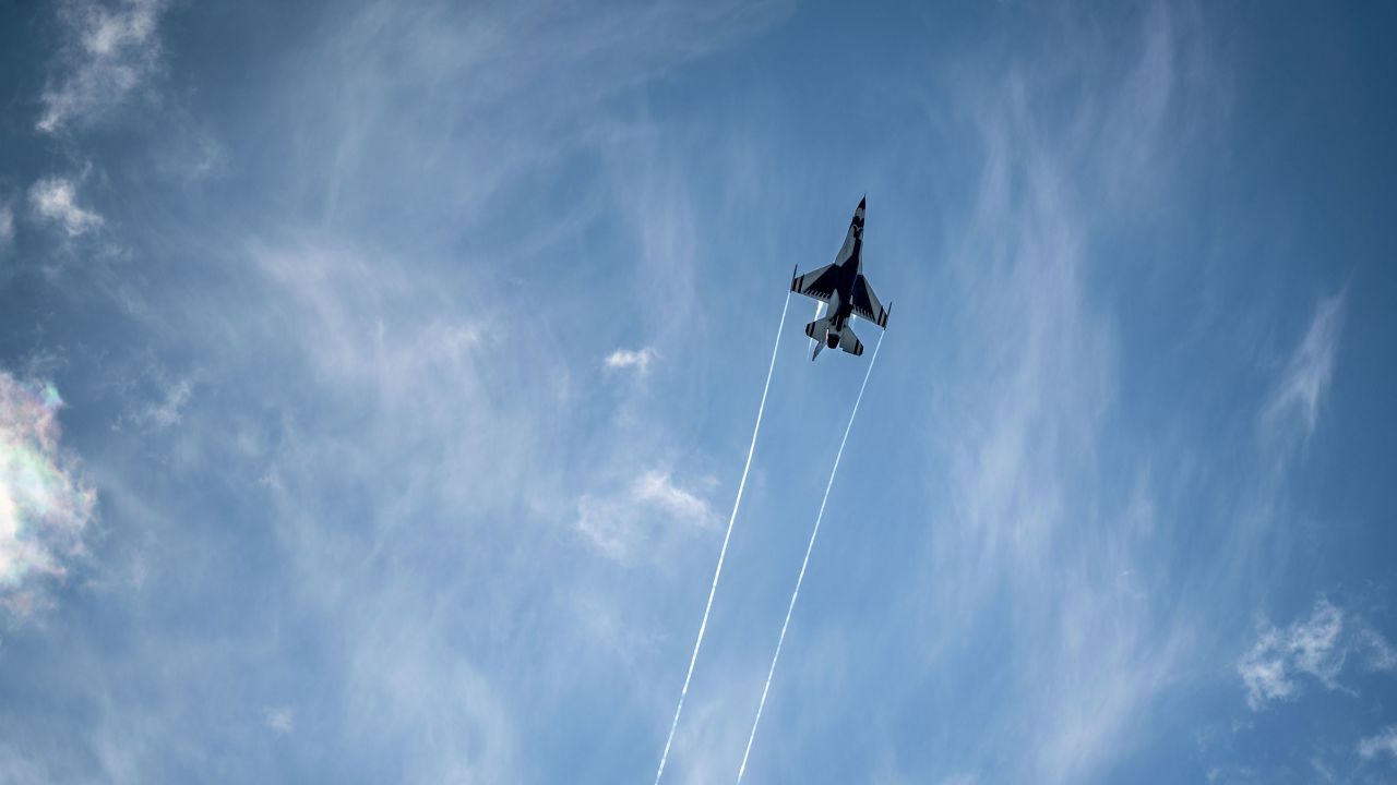 A US Air Force Thunderbird F-16D Fighting Falcon flies overhead.