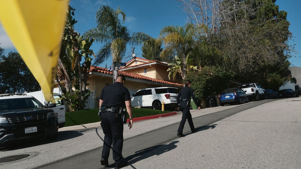 Police officers block the street access to a house where three people were killed and four others wounded in a shooting at a short-term rental home in an upscale neighborhood in Los Angeles on January 28, 2023. 