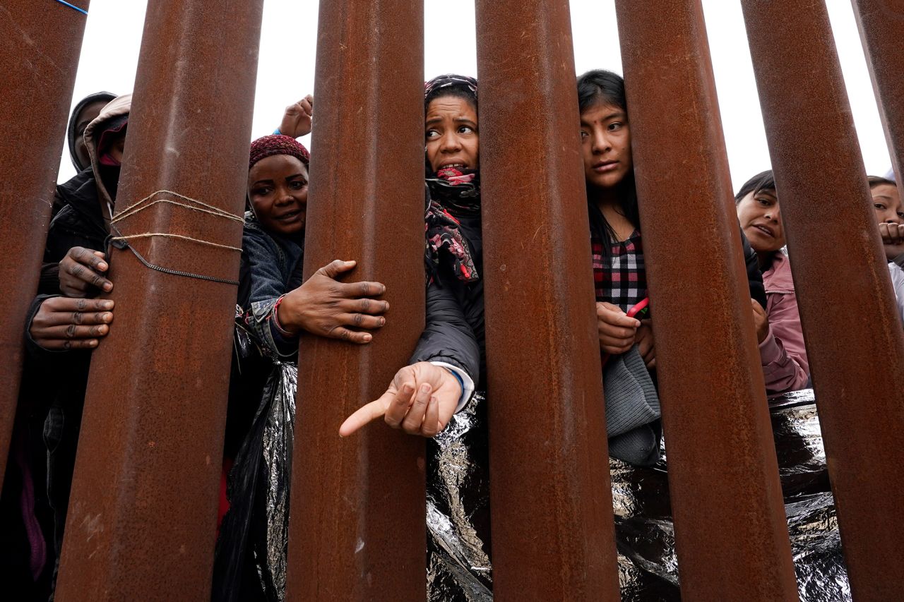 Migrants reach through a border wall for clothing handed out by volunteers near San Diego on May 12.