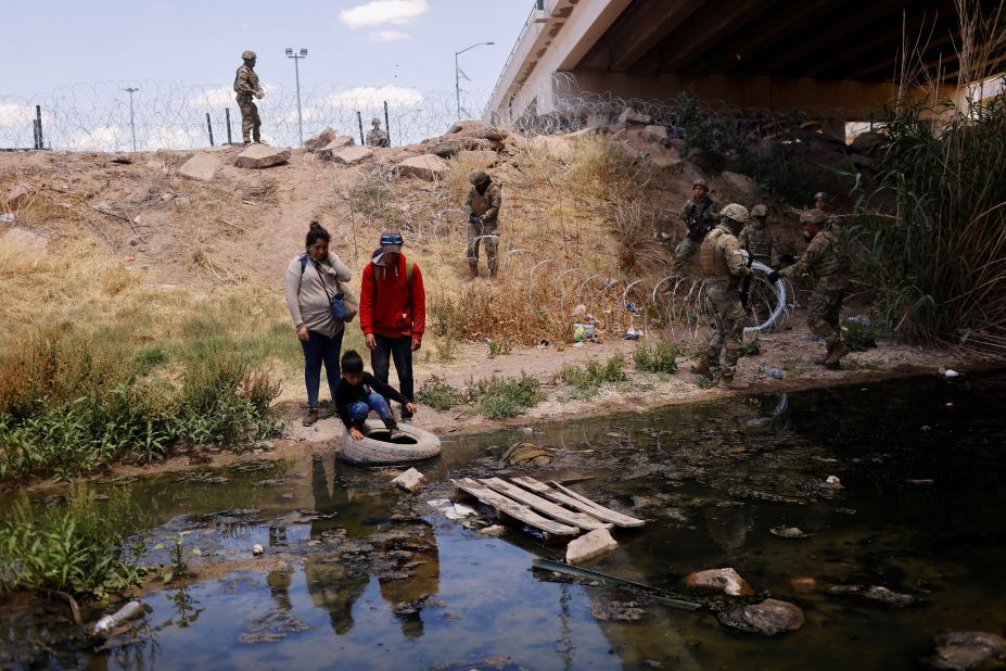 Migrants cross the Rio Bravo to return to Ciudad Juárez, Mexico, on Saturday, May 13, as members of the Texas National Guard extend razor wire at the border.