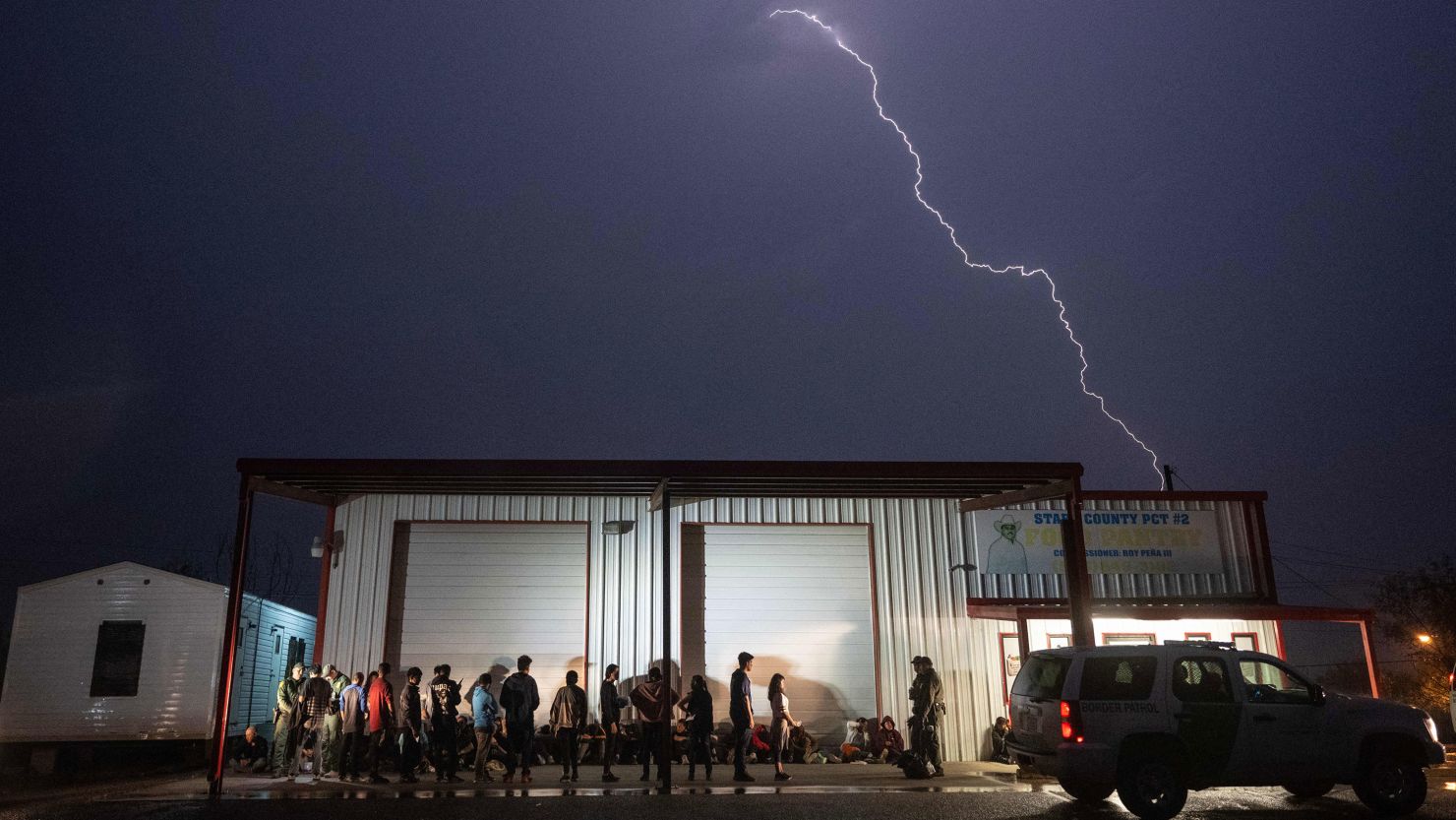 US Border Patrol agents keep watch over migrants that just turned themselves in after crossing over from Mexico as they wait for a bus to take them to a processing center in Fronton, Texas on May 12, 2023. 