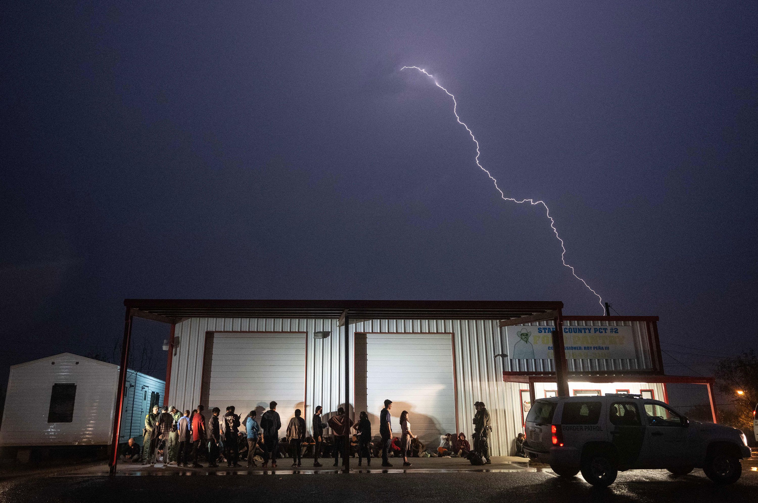 US Border Patrol agents watch over migrants waiting to take a bus to a processing center in Fronton, Texas, on Friday, May 12.