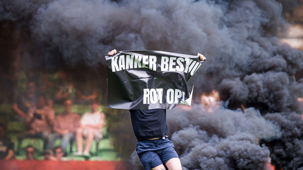 A supporter holding a banner runs onto the pitch at the Euroborg stadium.
