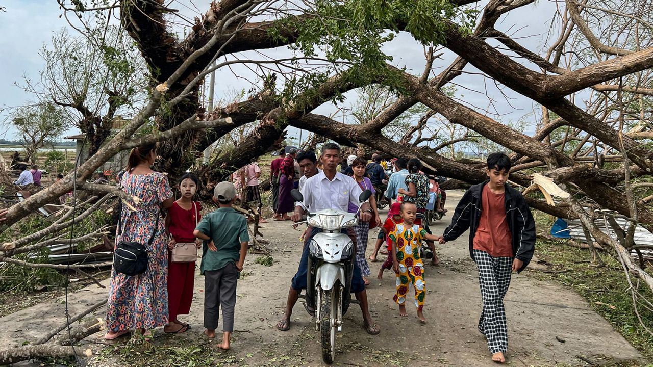 Residents walk past fallen trees in Kyauktaw in Myanmar's Rakhine state on May 15, 2023, after Cyclone Mocha crashed ashore. 