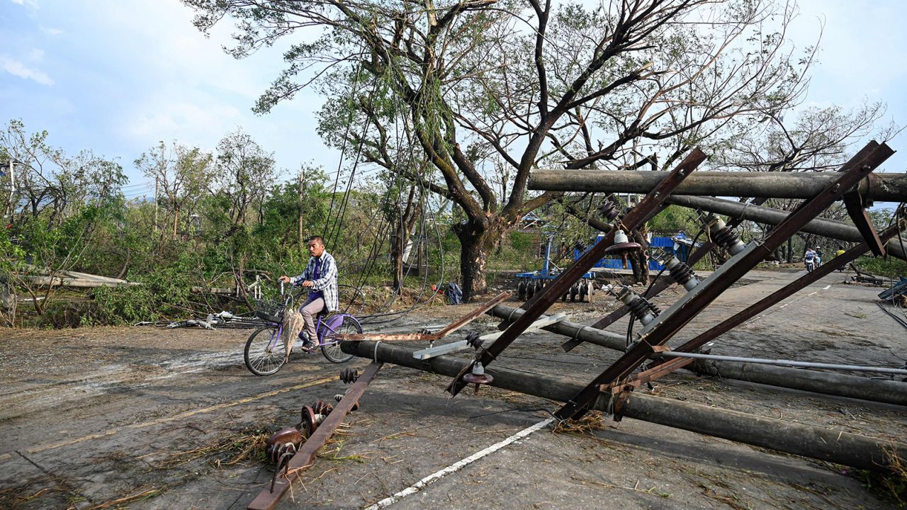 A resident drives his motorbike past fallen utility poles in Kyauktaw in Myanmar's Rakhine state on May 15, 2023, after Cyclone Mocha crashed ashore.