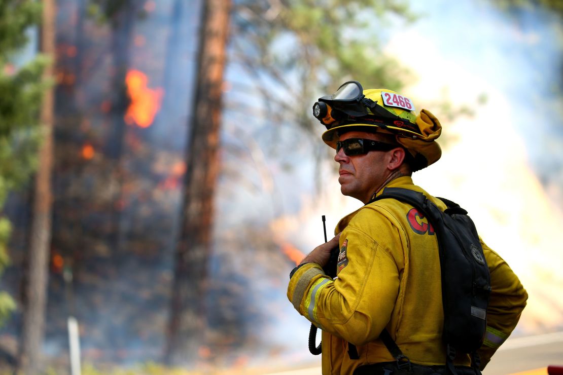 A firefighter monitors fire movement as it crosses Highway 299 in California.