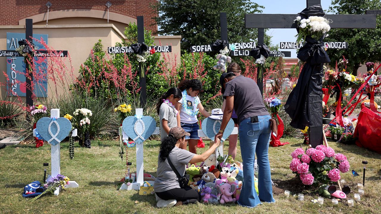 A mother and her children pray on May 9 at a cross that bears the name of one of her children's best friends at a memorial near the scene of the shooting.