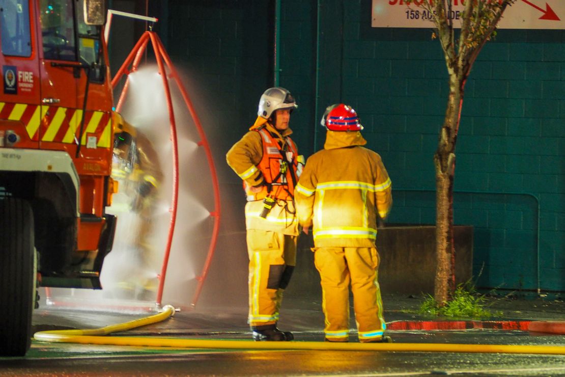 Firefighters stand outside the hostel where a fire broke out overnight. 