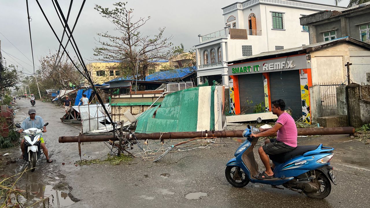 Residents ride motorcycles past broken utility poles in Sittwe, in Myanmar's Rakhine state, on May 15, 2023, after Cyclone Mocha made landfall.