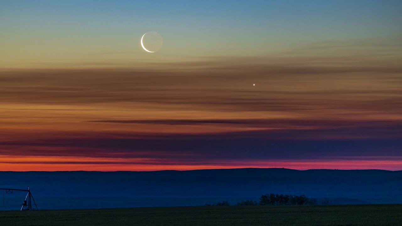 The conjunction of the waning crescent Moon with Venus as they were rising low in the northeast dawn sky on June 26, 2022, taken from home in southern Alberta, latitude 51° N. Earthshine is visible on the dark side of the Moon. The sky exhibits the wonderful transition of colours from the orange at the horizon through the spectrum to the blues at top. This is a single 1-second exposure with the RF70-200mm lens at 200mm and f/4 on the Canon R5 at ISO 400. (Photo by: Alan Dyer/VW Pics/Universal Images Group via Getty Images)