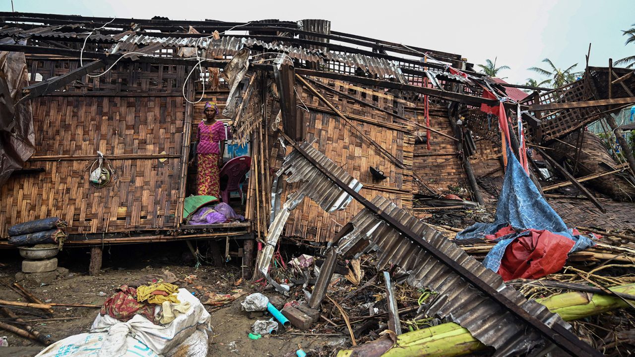 A Rohingya woman stands in her damaged house at Basara refugee camp in Sittwe on May 16 following Cyclone Mocha.