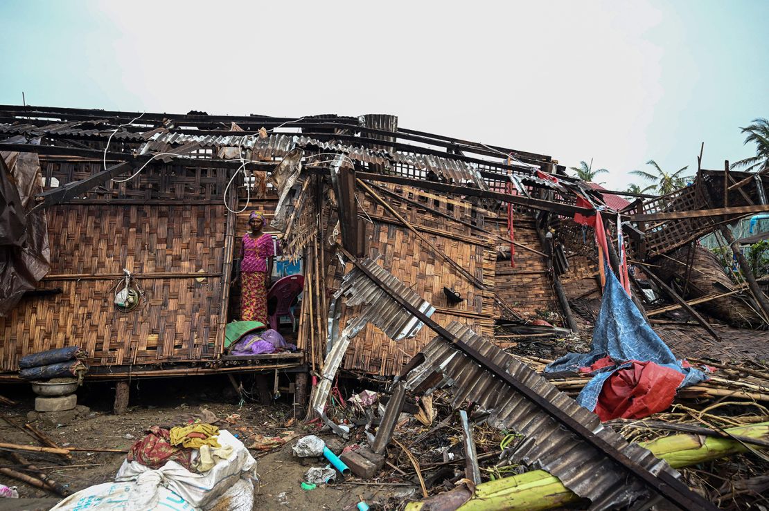 A Rohingya woman stands in her damaged house at Basara refugee camp in Sittwe on May 16 following Cyclone Mocha.