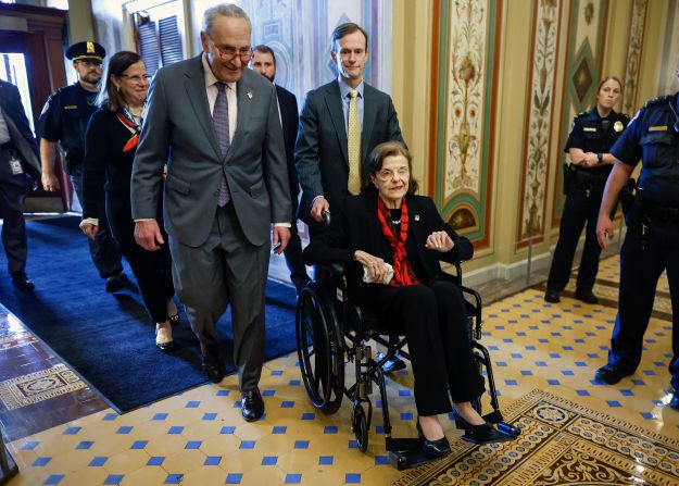 Senate Majority Leader Chuck Schumer escorts Feinstein as she arrives at the Capitol following a long absence due to health issues in 2023.