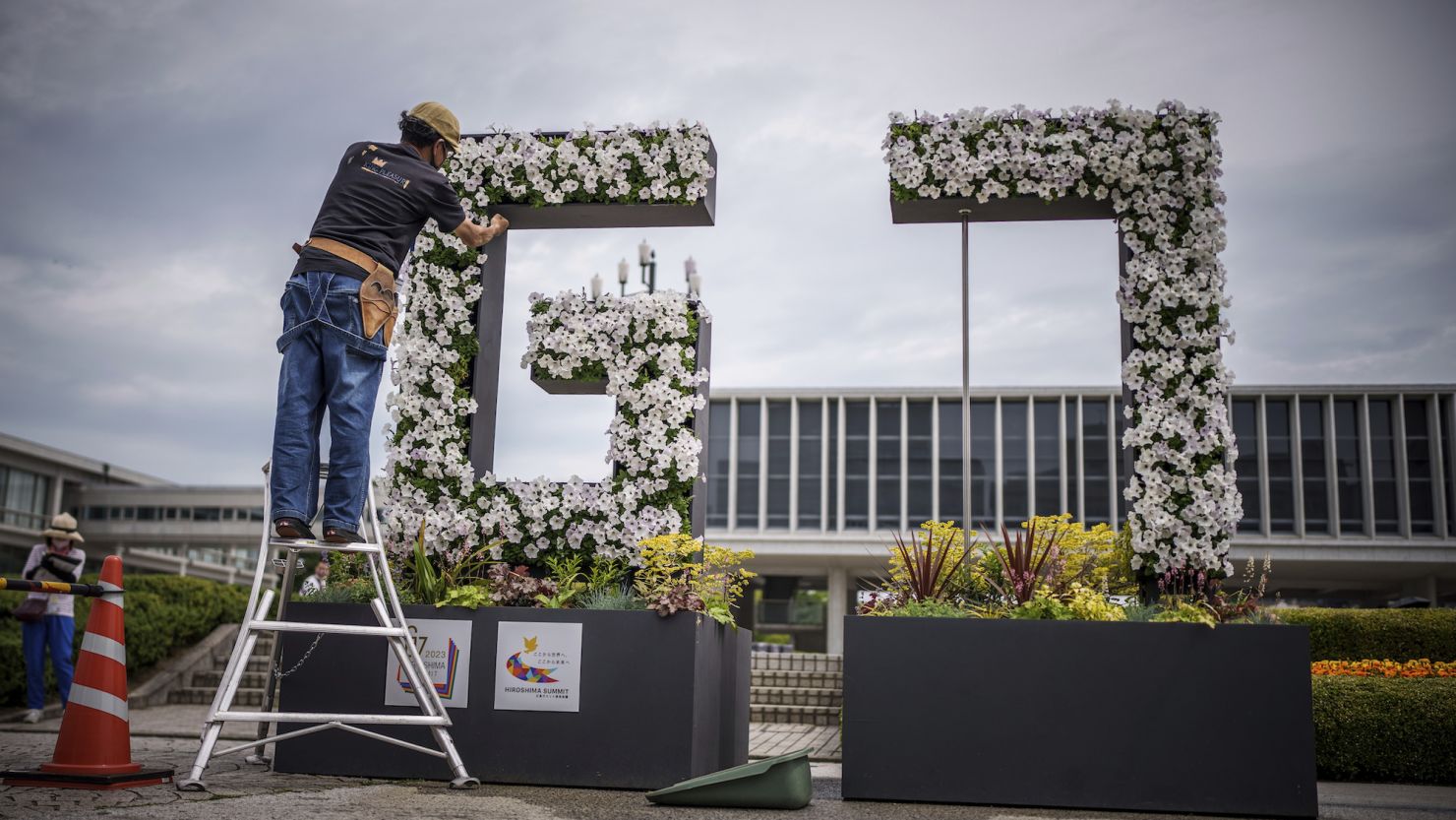 A gardener works on a G7 logo made of flowers with Genbaku Dome in the background in Hiroshima Peace Memorial Park on Thursday. 