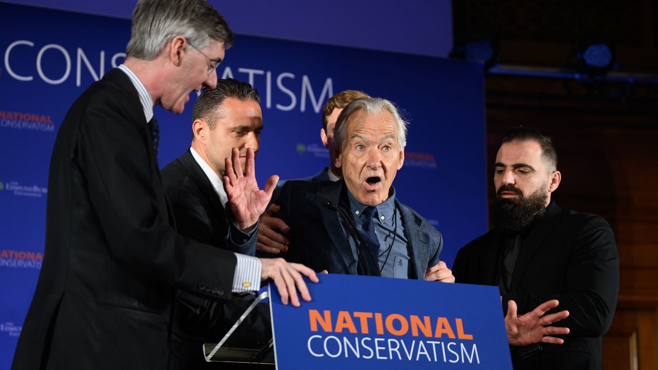 An Extinction Rebellion protester is escorted from the stage after interrupting a speech at the National Conservatism conference on May 15, 2023 in London.