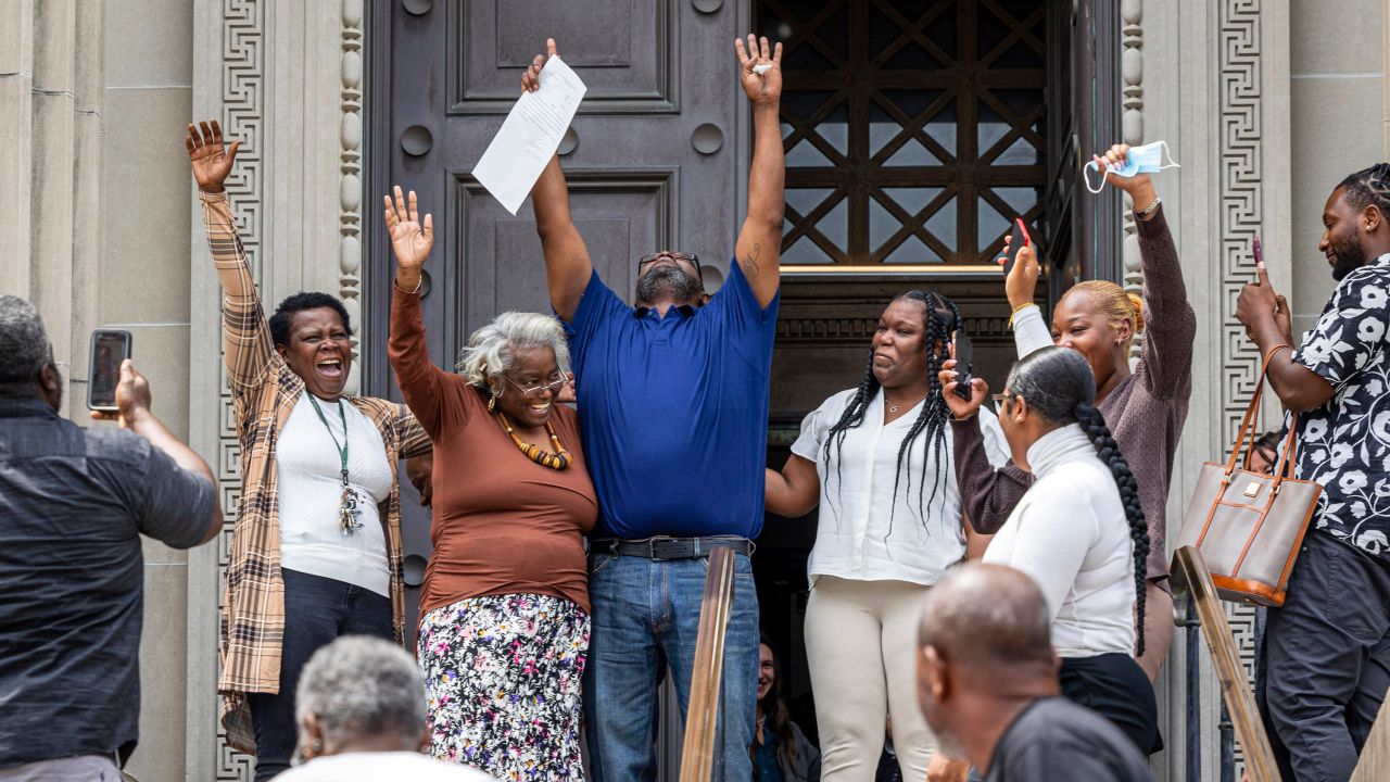 Patrick Brown, center in blue, raises his arms as he walks out a free man from Criminal District Court on Monday, May 8, 2023 in New Orleans after 20 years in jail for a rape the victim/survivor says he did not commit. (Chris Granger/The Advocate via AP)