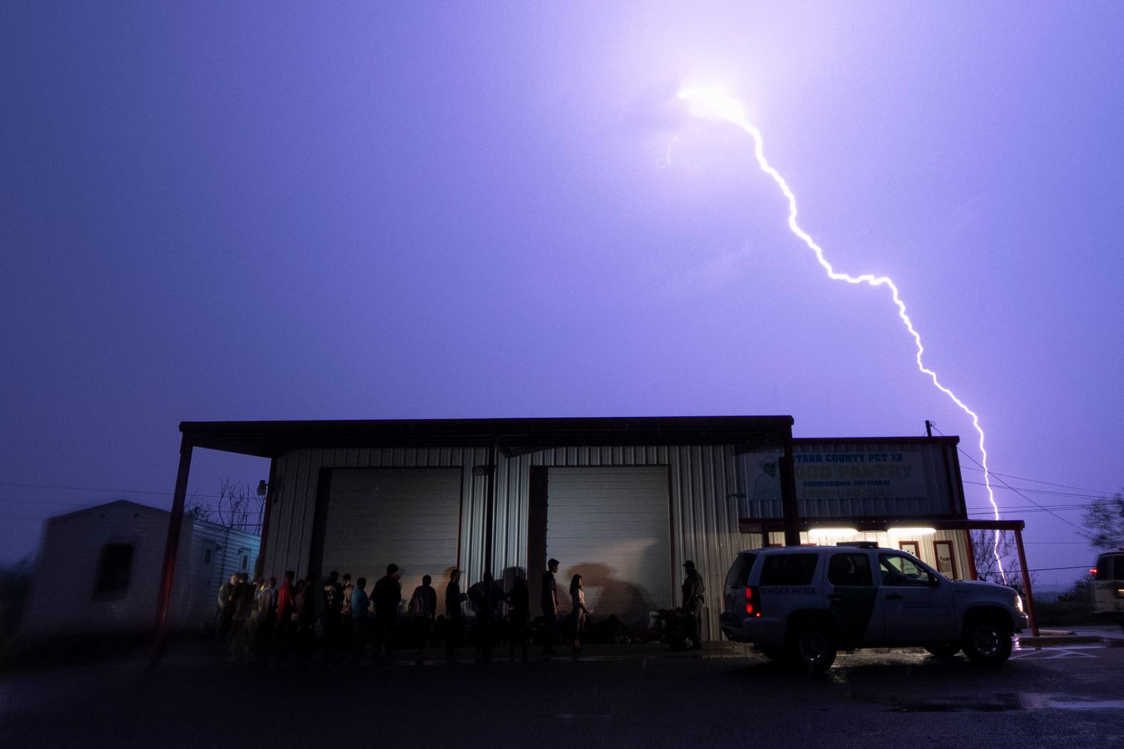 A lightning bolt is seen in the sky as migrants line up for processing in Fronton, Texas, on Saturday, May 13. The migrants had just crossed the US-Mexico border. The expiration of the border restriction policy known as Title 42 has so far brought <a href="index.php?page=&url=https%3A%2F%2Fwww.cnn.com%2F2023%2F05%2F14%2Fus%2Ftitle-42-border-immigration-sunday%2Findex.html" target="_blank">fewer migrant arrivals than expected</a>, but southern border communities still worry about overcrowded facilities for processing and detention.