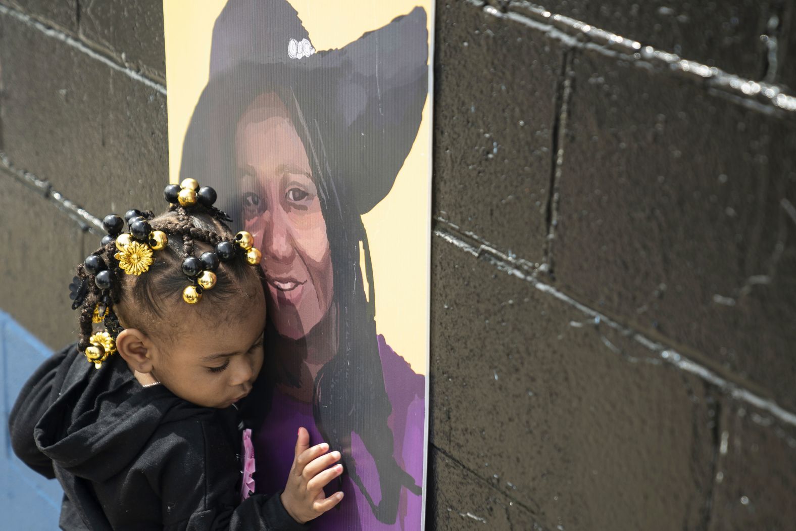 Naujaj Buchanan, 2, nestles close to a portrait of her godmother, Geraldine Talley, on Sunday, May 14, across the street from the Buffalo, New York, supermarket where Talley was killed in a <a href="index.php?page=&url=https%3A%2F%2Fwww.cnn.com%2F2023%2F05%2F17%2Feurope%2Fitaly-flooding-three-killed-rain-intl%2Findex.html" target="_blank">mass shooting last year</a>.
