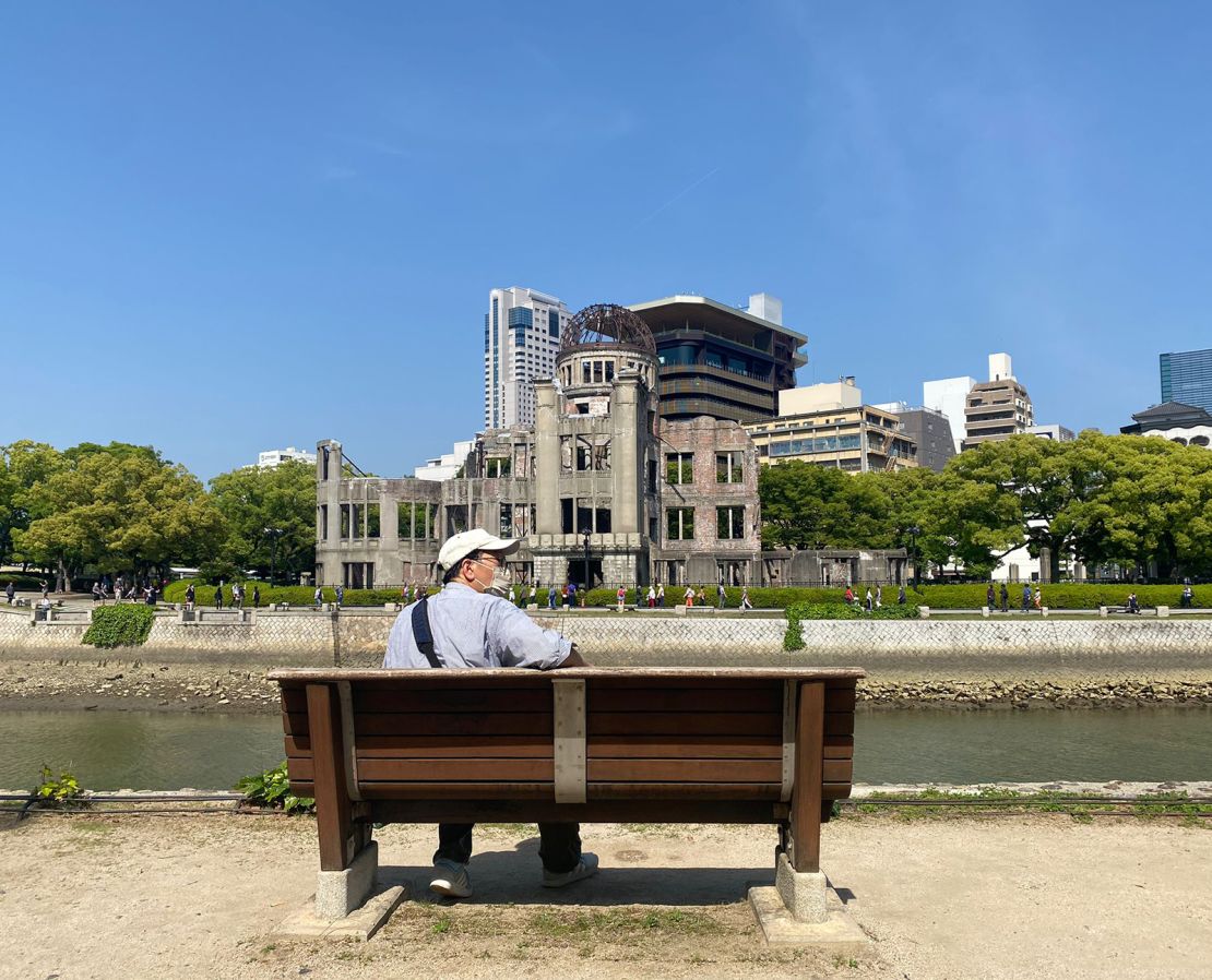 A man relaxes alongside the river on a bench overlooking the Genbaku Dome.