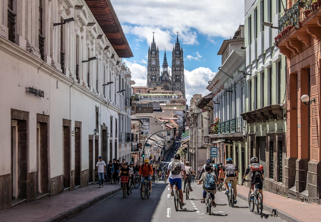 JA571E Bikers and pedestrians on a sunday closed street of Quito and Basilica del Voto Nacional - Quito, Ecuador