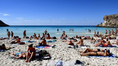 Tourists sunbathe on the beach of the Isola dei Conigli (Rabbit Island) in Lampedusa on September 27, 2018. - Five years after the worst shipwreck of its history, the Italian Pelagie Island of Lampedusa relies on the flood of tourists to make a fresh start, though it might become a gateway to Europe again. (Photo by Alberto PIZZOLI / AFP) / TO GO WITH AFP STORY BY FANNY CARRIER        (Photo credit should read ALBERTO PIZZOLI/AFP via Getty Images)