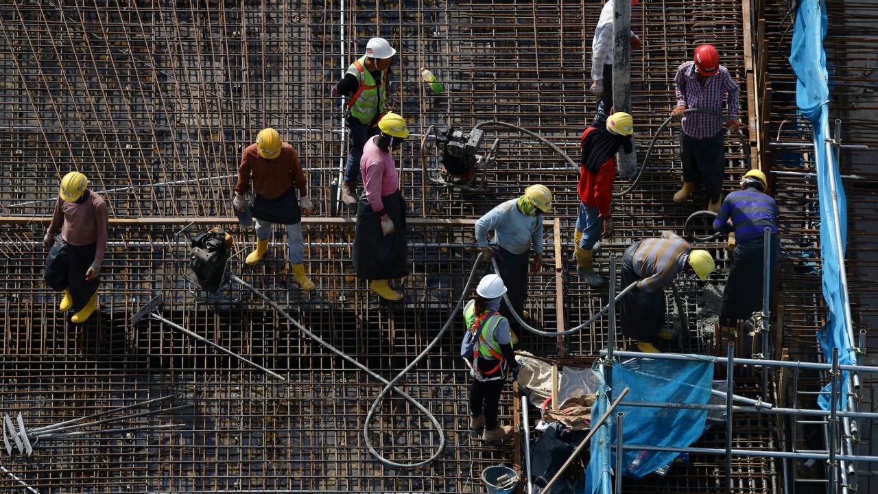 Migrant laborers toil under the hot sun at a construction site in Singapore on May 3, 2023.