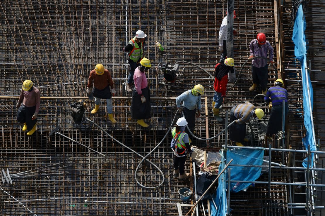 Migrant laborers toil under the hot sun at a construction site in Singapore on May 3, 2023.