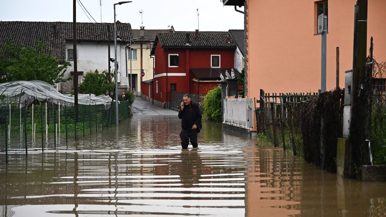 Un residente local usa un teléfono mientras camina por una calle inundada en el pueblo de Carde, Cuneo, cerca de Turín, en el noroeste de Italia, el domingo.